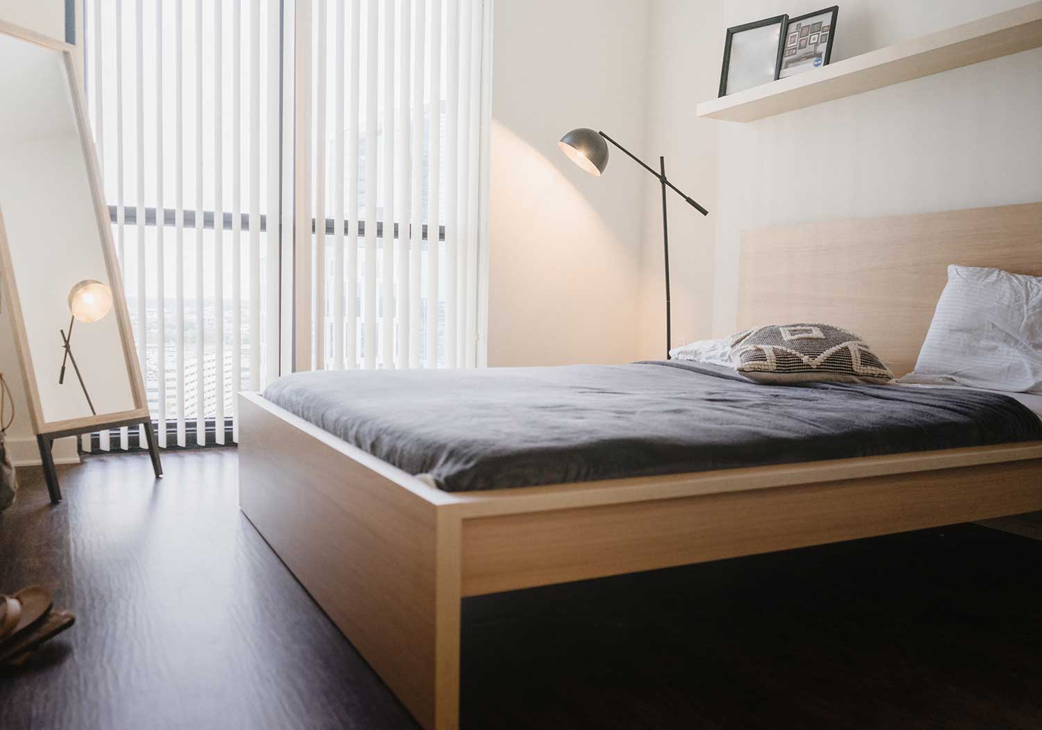 Minimal bedroom furniture arrangement with bed and stand mirror.