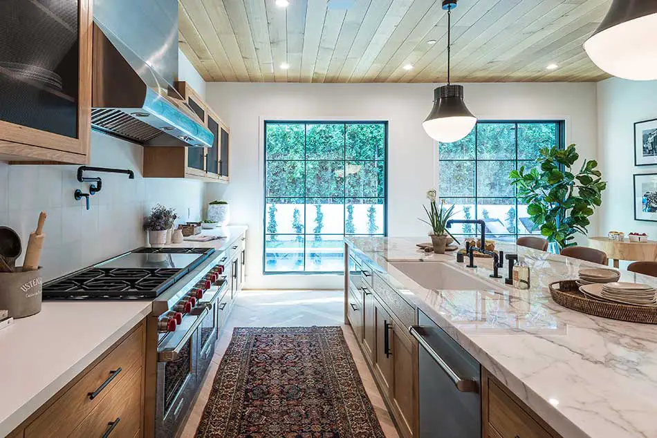 Kitchen with large windows and greenery.