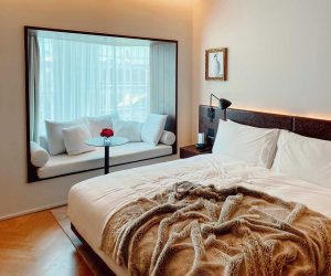 Hotel room with double bed and bench in front of the window.