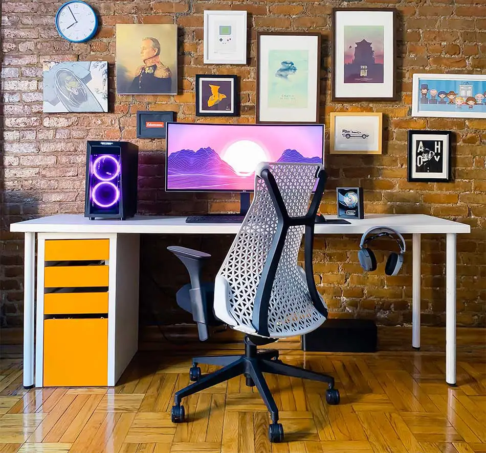 An ergonomic office chair with desk and wall gallery.