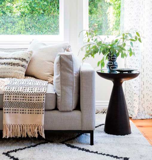 Black wooden side table and sofa in front of the window.